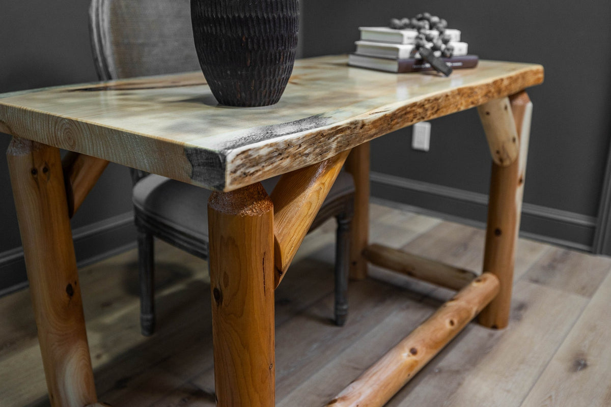 May include: A rectangular desk featuring a live edge wooden slab top with a light-colored finish and a smooth surface. The base is constructed from four thick, cylindrical cedar log legs connected by horizontal log stretchers and angled supports.
