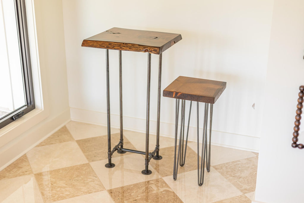 May include: Two wooden tables with metal legs. The larger table has a rectangular top with a live edge and a black metal base. The smaller table has a square top and hairpin legs.
