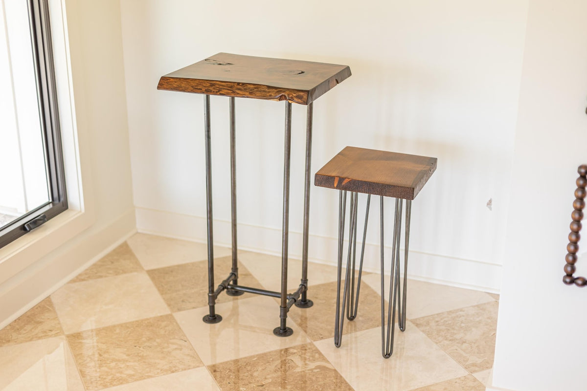 May include: Two wooden tables with metal legs. The larger table has a rectangular top with a live edge and a black metal base. The smaller table has a square top and hairpin legs.