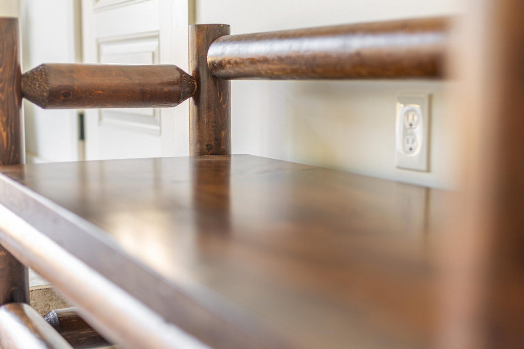 May include: A dark brown wooden bench featuring a smooth, polished flat seat and cylindrical log-style supports. The frame is constructed from thick, rounded timber pieces with a glossy finish, showcasing the natural wood grain and texture.