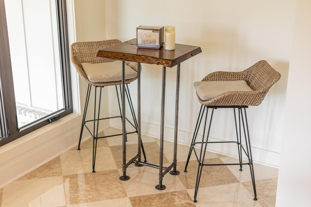May include: A wooden table with a live edge top and black metal legs. Two wicker chairs with black metal frames and beige cushions are placed around the table.